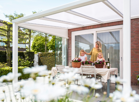 Een vrijstaande Verasol veranda met een modern vlak dak design en schuine houten staanders, geplaatst in een tuin met een groot gazon.